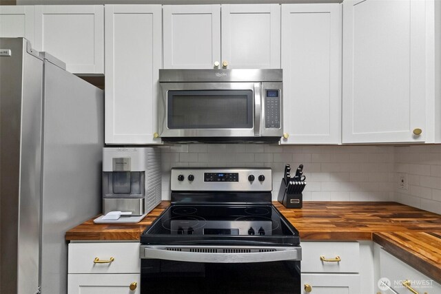 kitchen featuring stainless steel appliances, butcher block counters, white cabinetry, and decorative backsplash