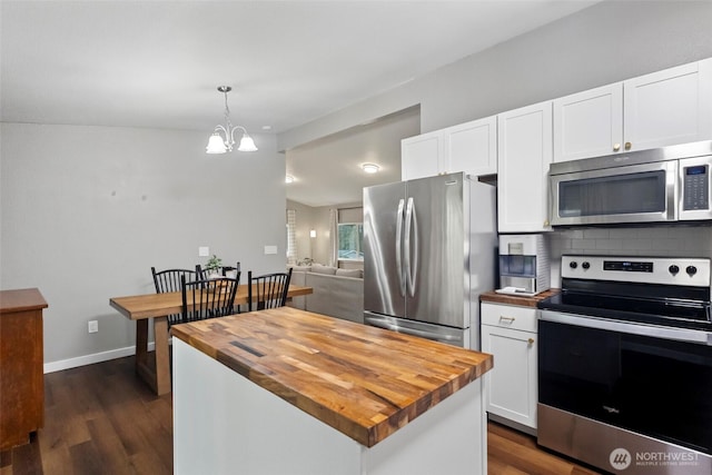 kitchen with stainless steel appliances, white cabinets, butcher block countertops, and backsplash