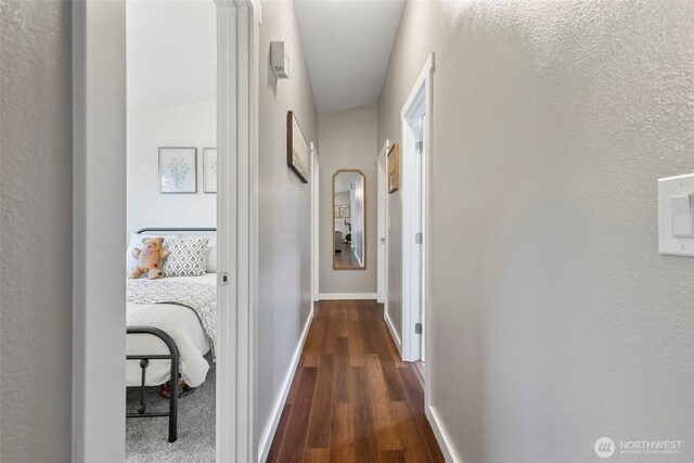 corridor with baseboards and dark wood-type flooring