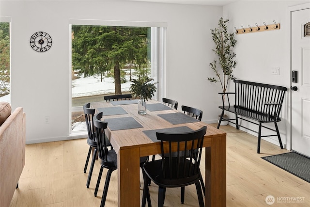 dining space featuring light wood-type flooring and baseboards