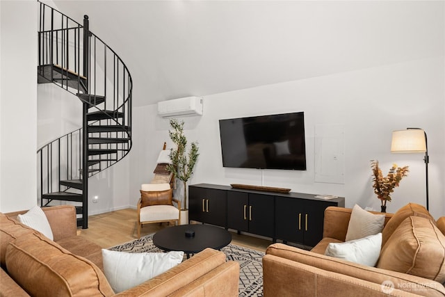 living area with stairway, light wood-style flooring, baseboards, and a wall mounted AC