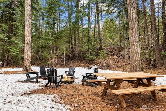 view of yard featuring a fire pit and a view of trees