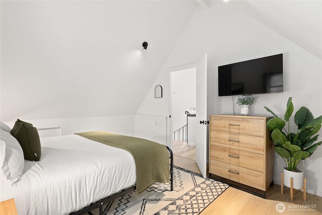 bedroom with lofted ceiling and light wood-style floors