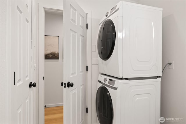 clothes washing area with laundry area, light wood finished floors, and stacked washing maching and dryer