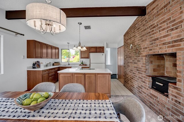 kitchen featuring freestanding refrigerator, a chandelier, a kitchen island, light countertops, and hanging light fixtures