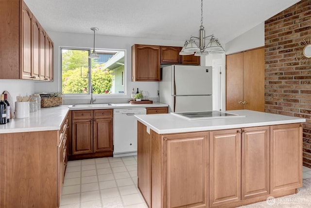 kitchen featuring white appliances, a sink, vaulted ceiling, pendant lighting, and light countertops