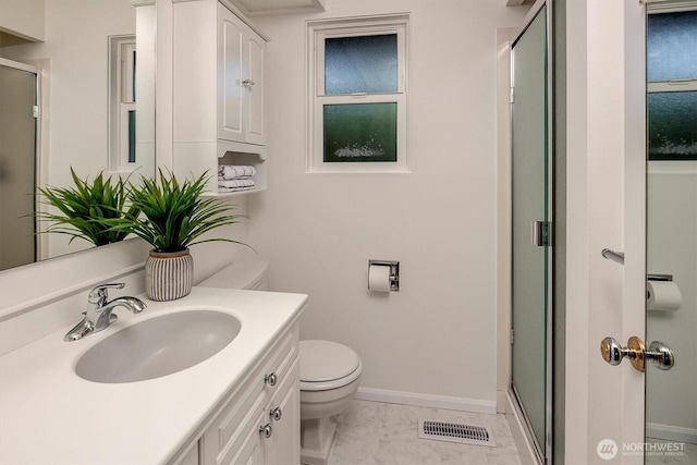 bathroom featuring a shower stall, toilet, marble finish flooring, and baseboards