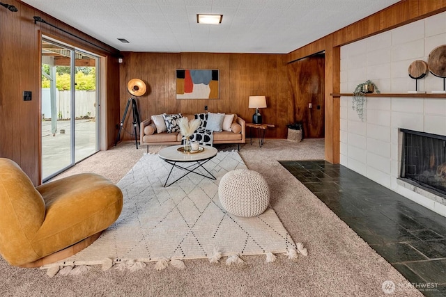living area featuring wood walls, carpet flooring, and a fireplace