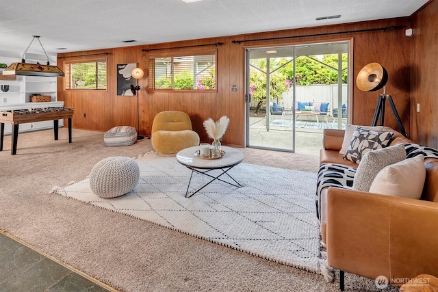 carpeted living room featuring wooden walls