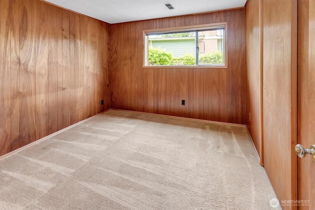 unfurnished room featuring wood walls and carpet floors