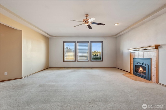 unfurnished living room with carpet, baseboards, ceiling fan, and a tiled fireplace