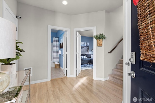 foyer with visible vents, baseboards, light wood-style flooring, and stairs