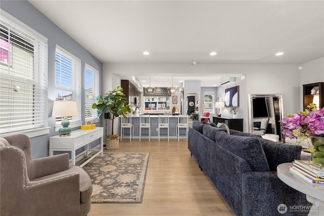 living area with recessed lighting, light wood-style flooring, and a wall unit AC