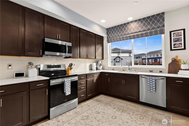 kitchen featuring dark brown cabinetry, stainless steel appliances, light countertops, and a sink