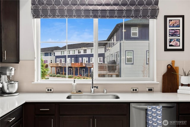 kitchen with decorative backsplash, dark brown cabinets, dishwasher, and a sink