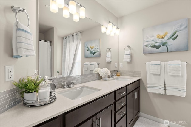 full bathroom with decorative backsplash, double vanity, baseboards, and a sink