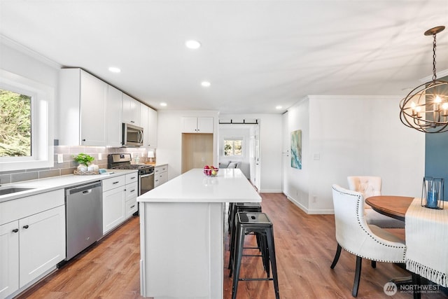 kitchen featuring light wood finished floors, tasteful backsplash, a barn door, appliances with stainless steel finishes, and a breakfast bar