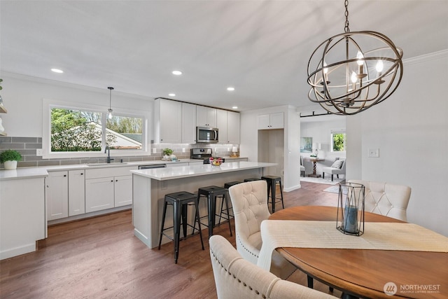 kitchen with tasteful backsplash, white cabinets, a kitchen island, appliances with stainless steel finishes, and a sink