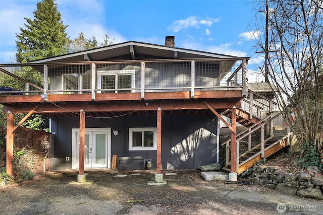 rear view of house featuring a deck, french doors, stairway, and a chimney