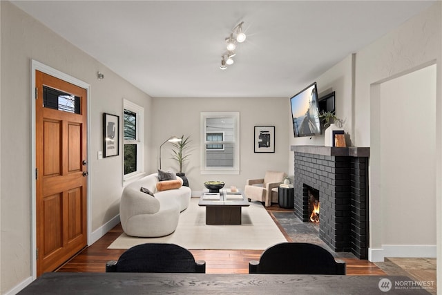 living room with a brick fireplace, wood finished floors, and baseboards