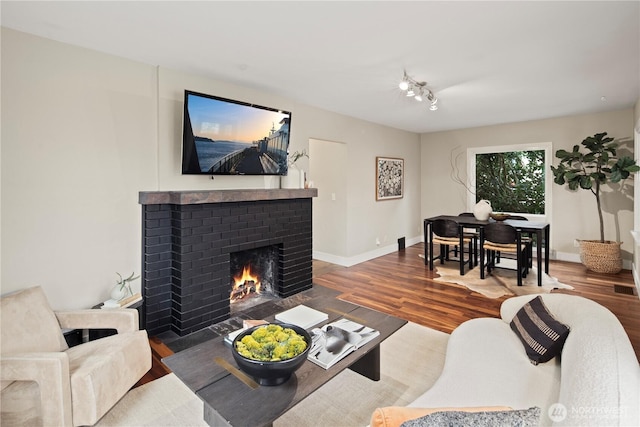 living room with a fireplace, baseboards, and wood finished floors