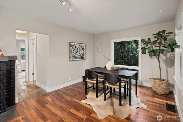 dining room featuring track lighting, wood finished floors, visible vents, and baseboards