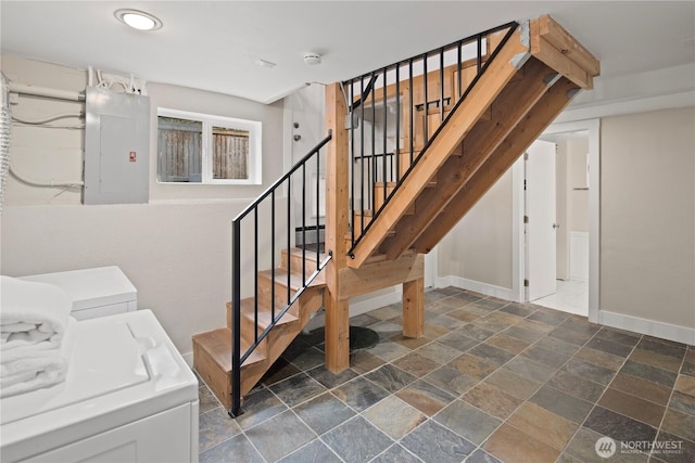 stairway with stone finish flooring, electric panel, baseboards, and separate washer and dryer