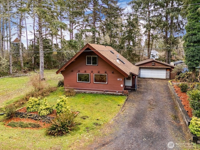 chalet / cabin with a garage, a front lawn, and an outdoor structure