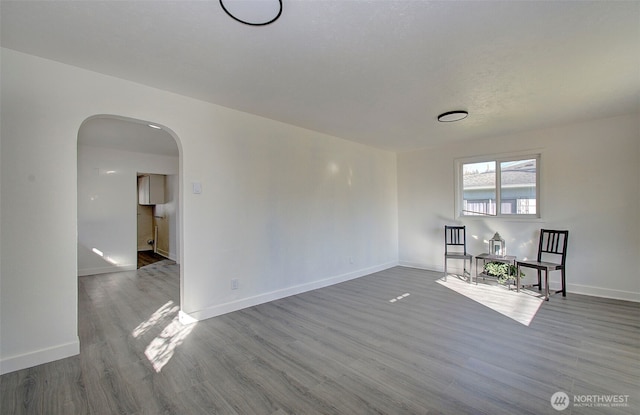 105 Redpath St, Kelso, WA 98675 - unfurnished living room featuring arched walkways, wood finished floors, and baseboards
