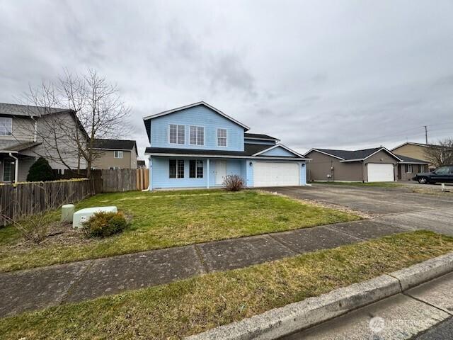 traditional home with a garage, fence, aphalt driveway, and a front yard