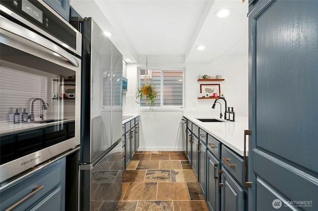 kitchen with a sink, stone tile floors, recessed lighting, light countertops, and dishwasher