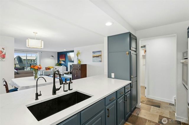 kitchen with light countertops, stone finish flooring, open floor plan, and a sink