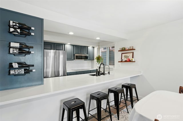 kitchen with a kitchen bar, a sink, recessed lighting, appliances with stainless steel finishes, and a peninsula