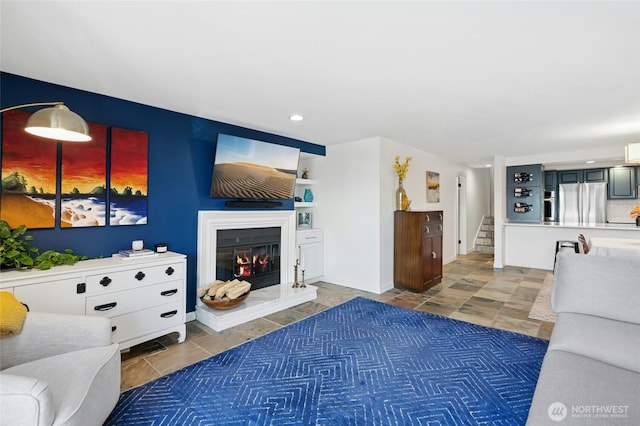 living area with recessed lighting, stairway, baseboards, and a glass covered fireplace