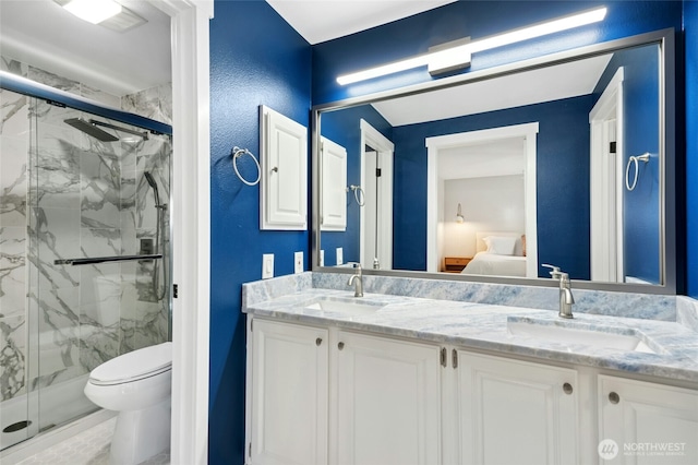 bathroom featuring a sink, a marble finish shower, and double vanity