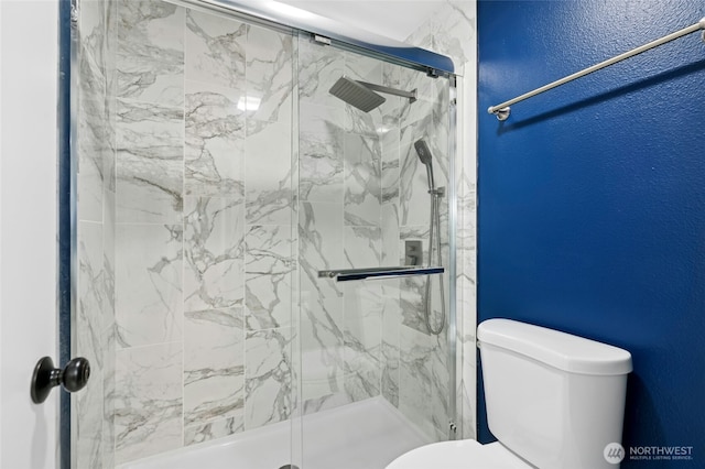 full bathroom featuring a marble finish shower, toilet, and a textured wall