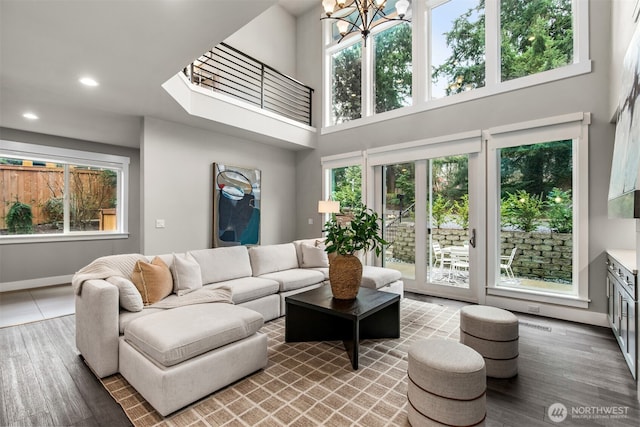 living area with recessed lighting, a high ceiling, wood finished floors, a chandelier, and baseboards