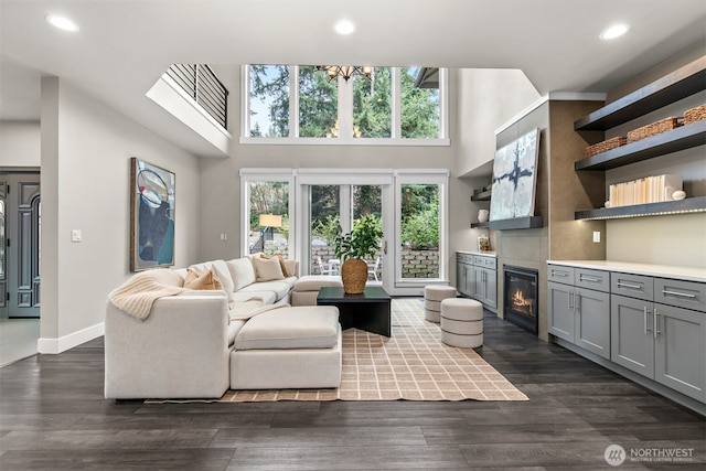 living area with dark wood finished floors, a glass covered fireplace, and a wealth of natural light