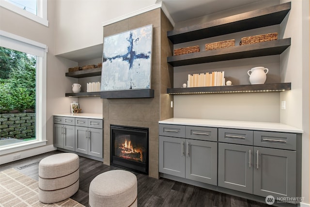 bar featuring dark wood-style floors, visible vents, and a tile fireplace