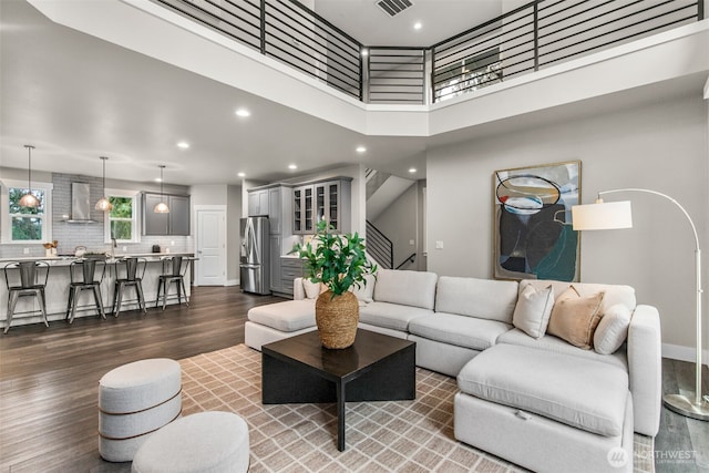 living area featuring stairs, a high ceiling, dark wood finished floors, and recessed lighting