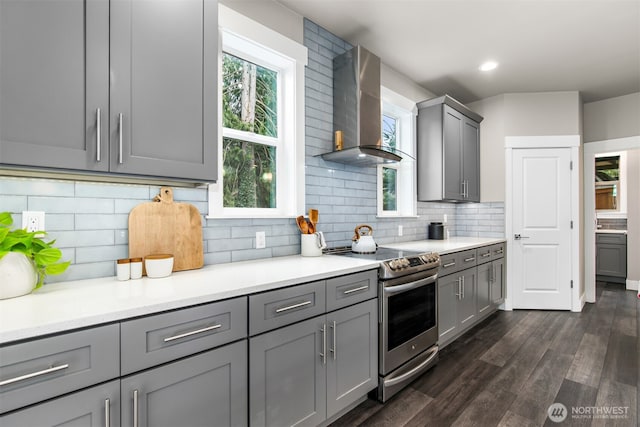 kitchen with dark wood-style flooring, gray cabinets, electric range, decorative backsplash, and wall chimney exhaust hood