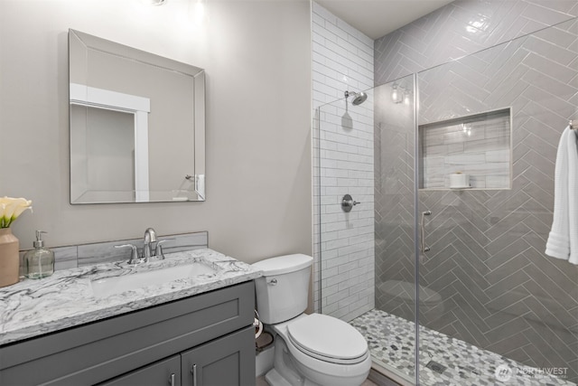 bathroom with a stall shower, vanity, and toilet