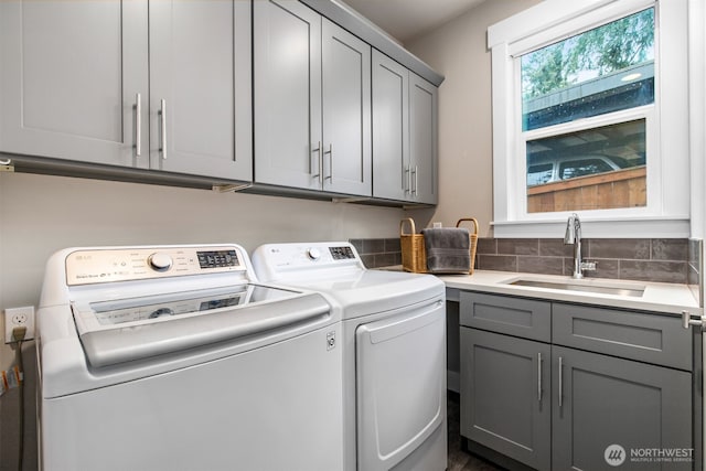 laundry room with cabinet space, a sink, and independent washer and dryer