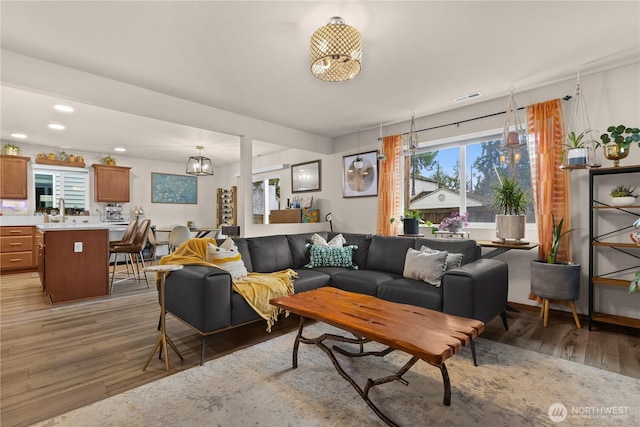 living room with light wood-type flooring, visible vents, and recessed lighting