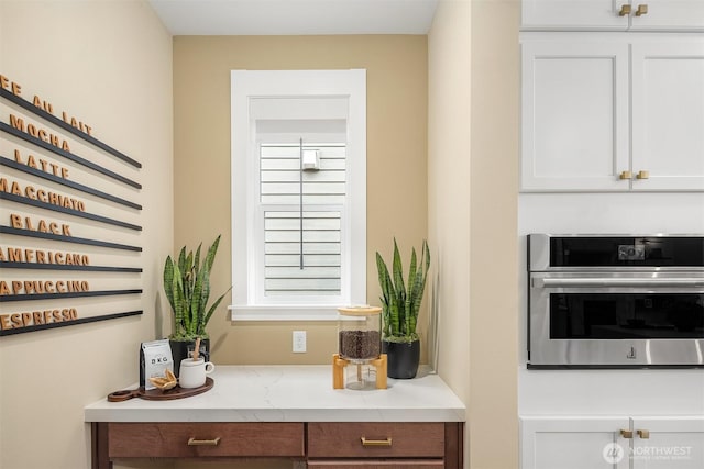 interior space with light stone countertops, white cabinetry, and stainless steel oven