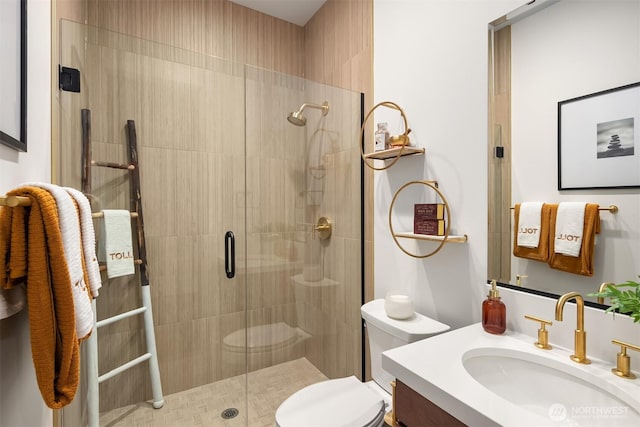 bathroom featuring toilet, a stall shower, and vanity