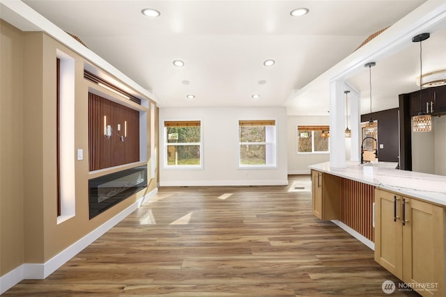 kitchen featuring light wood-style flooring, light stone counters, recessed lighting, and baseboards