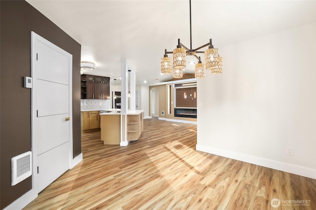 kitchen with visible vents, backsplash, light countertops, light wood-type flooring, and open shelves