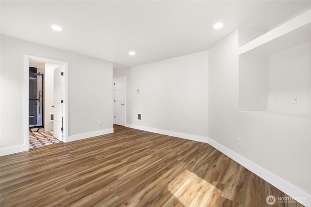 spare room featuring recessed lighting, baseboards, and wood finished floors