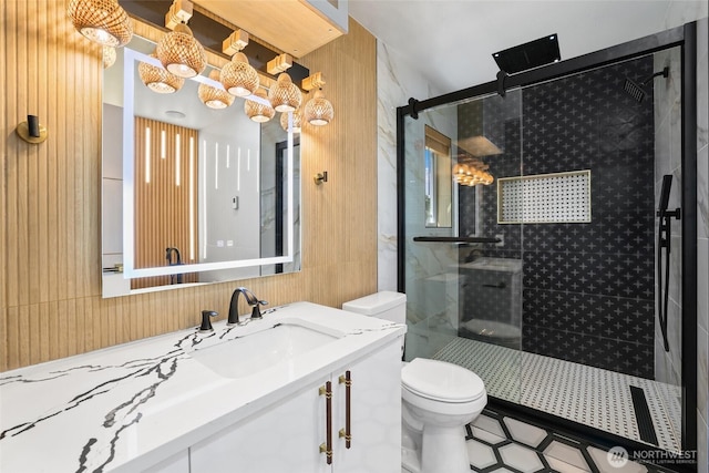 full bath with vanity, a shower stall, toilet, and wood walls